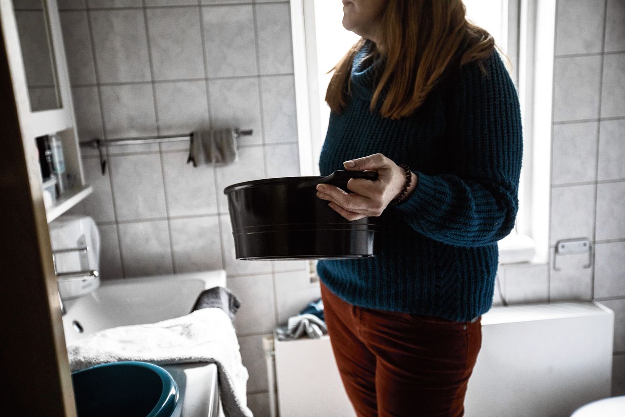 Een vrouw wast zich met warm water uit een pannetje. Voor sommige mensen zijn de rekeningen zo hoog geworden dat ze op allerlei manieren energie proberen te besparen.