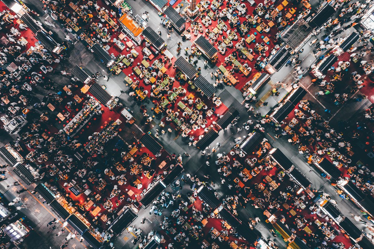 Een drone-foto van een drukbezochte nachtelijke voedselmarkt.