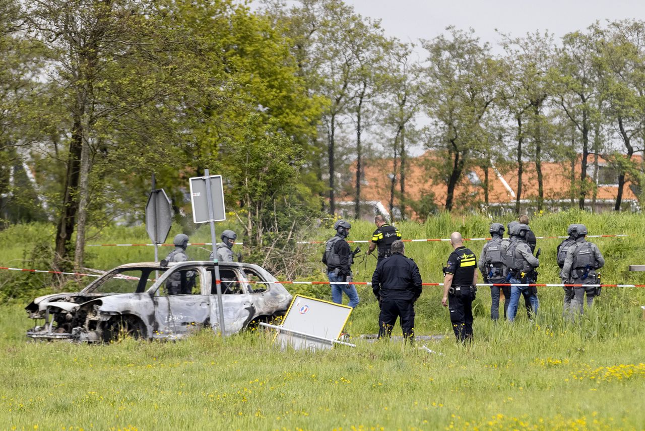 Politie-eenheden staan bij een uitgebrande auto in een weiland bij Broek in Waterland.