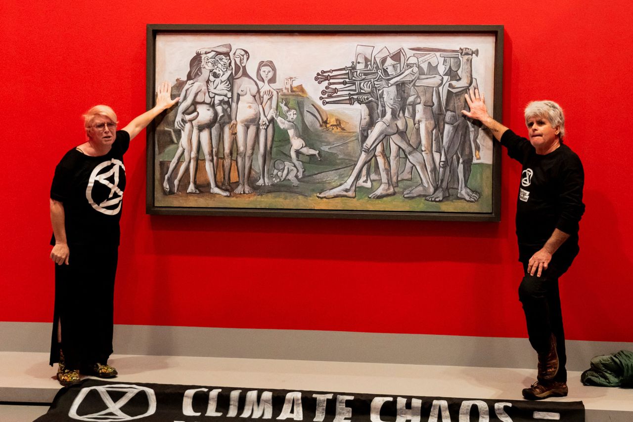 Klimaatactivisten in de National Gallery of Victoria in Melbourne, met hun handen vastgelijmd aan een schilderij van Picasso uit 1951, dat de verschikkingen van de Korea-oorlog toont. Het schilderij bleef onbeschadigd.