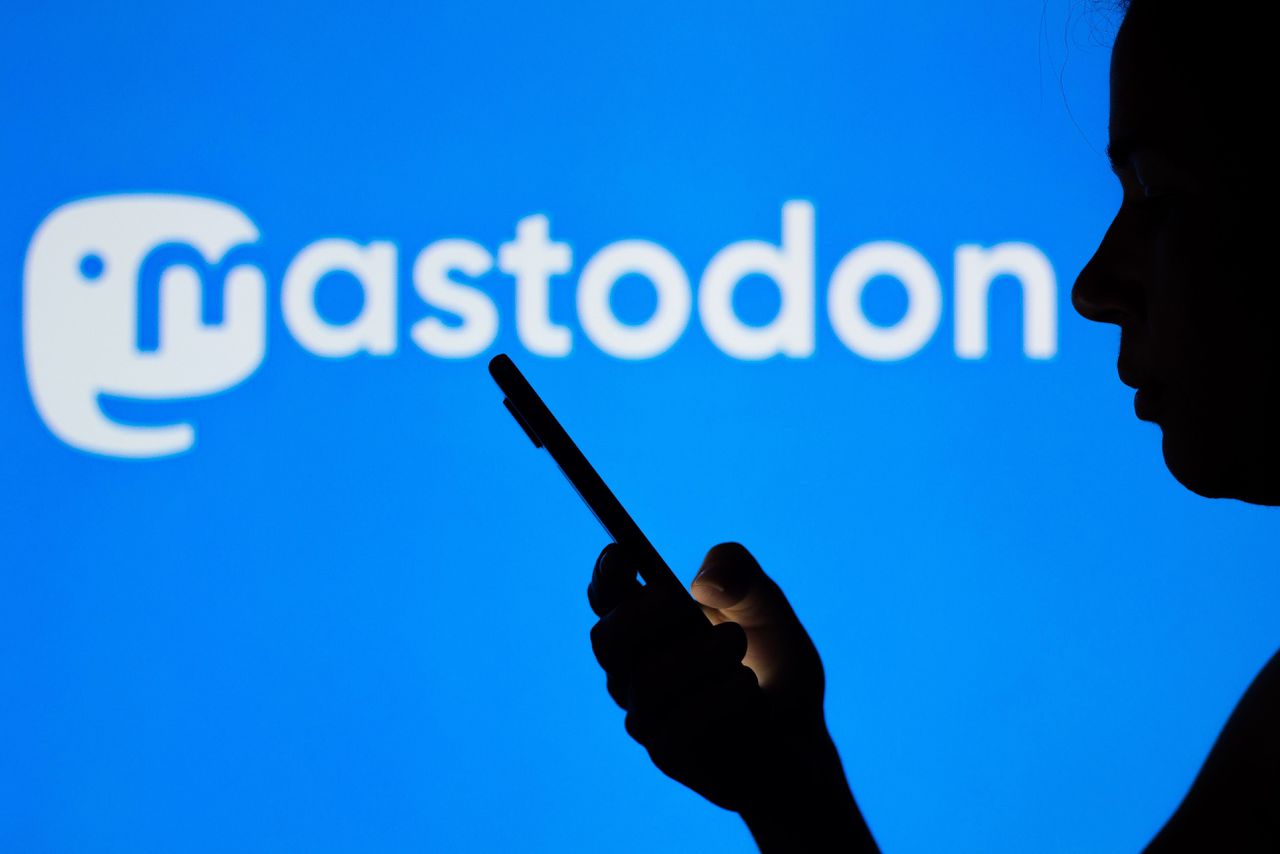 Silhouet van een vrouw, tegen de achtergrond van het logo van Mastodon.