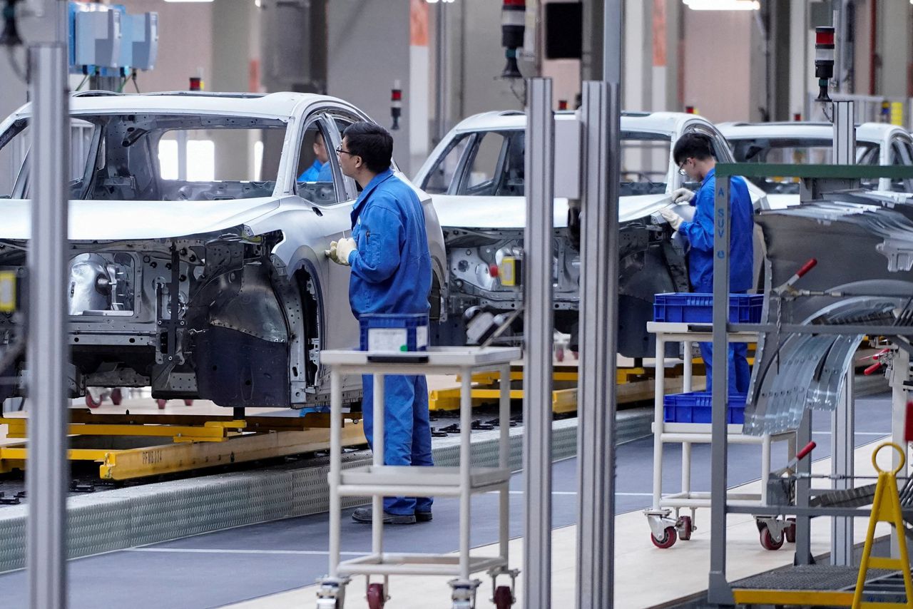 Chinese arbeiders monteren elektrische auto’s in een Volkswagen-fabriek in het Chinese Shanghai.