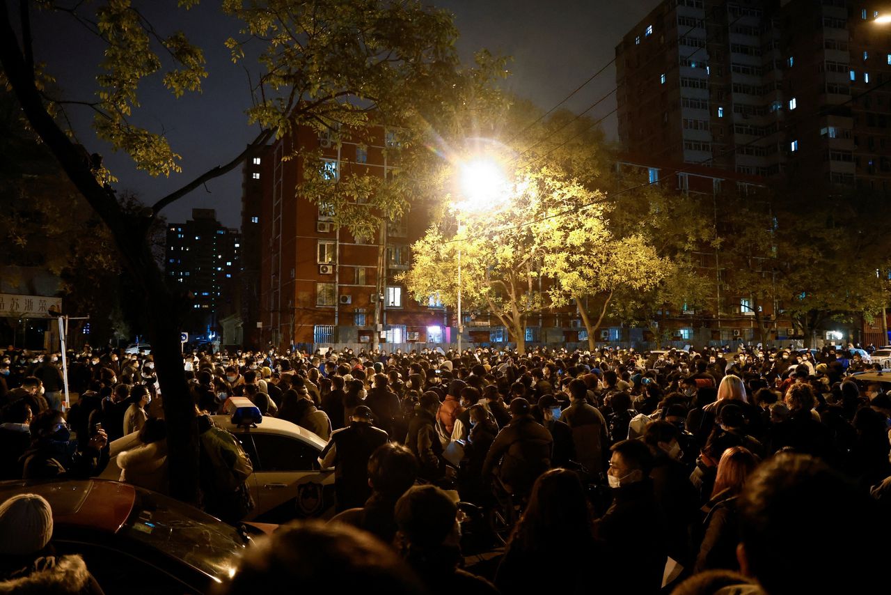 Inwoners van Beijing nemen deel aan een wake voor de slachtoffers van een brand in de stad Ürümqi tijdens een coronalockdown. Ze houden witte vellen papier omhoog uit protest tegen coronamaatregelen.