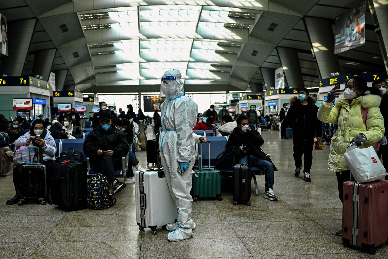 Reiziger in beschermende kleding op een treinstation in Beijing.