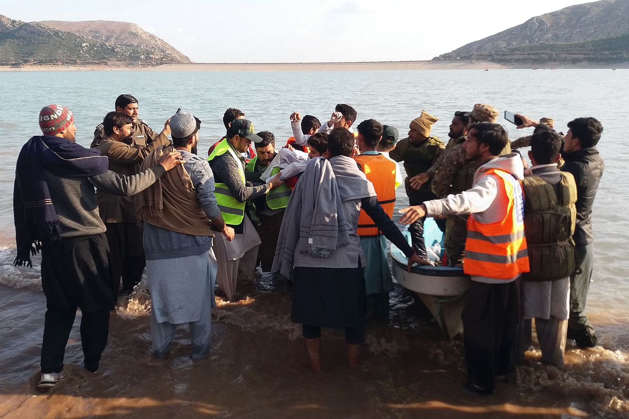 Reddingswerkers tillen het lichaam van een kind uit het water bij het Tanda Dam-meer in Pakistan.