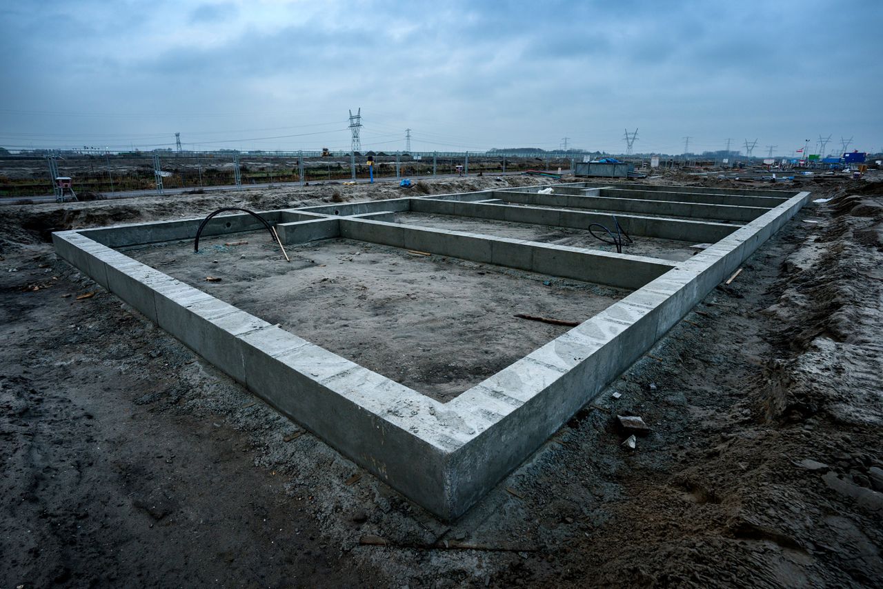 Een bouwplaats van Van Wijnen in Weesp. De drassige grond rond Amsterdam biedt te weinig stabiliteit, en moet daarom opgehoogd worden met zand uit het IJsselmeer. Dat ophoogzand moet vervolgens tien maanden tot een jaar inklinken, om een stevige basis voor de nieuwbouw te krijgen.