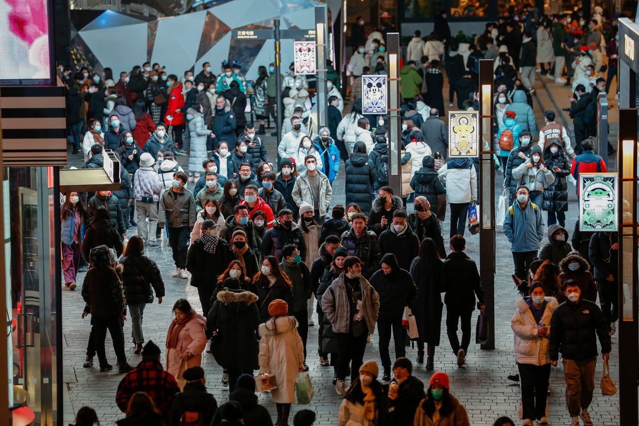 Mensen lopen langs een winkelgebied tijdens een uitbraak van Covid-19 tijdens oudejaarsavond in Beijing.