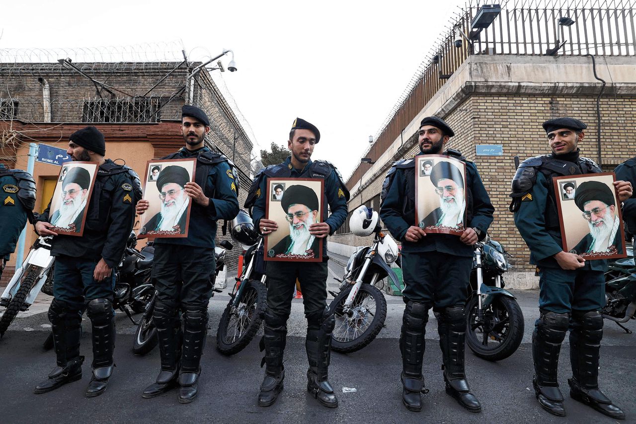 Iraanse agenten houden een beeltenis vast van ayatollah Khame-nei bij de Franse ambassade in Teheran, uit protest tegen Charlie Hebdo-cartoons. Foto Atta Kenare/ AFP