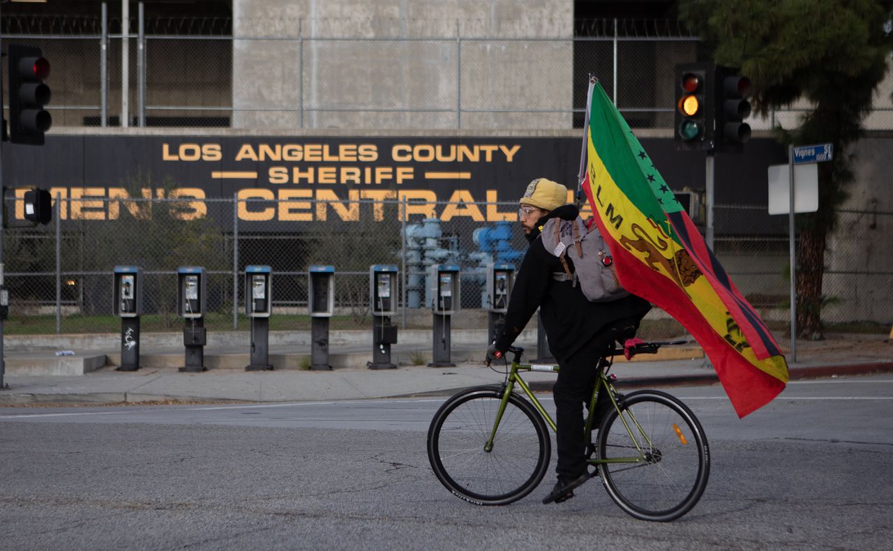 Een Black Lives Matter-demonstrant rijdt rond met een vlag van de beweging bij een protest bij een gevangenis in Los Angeles, begin 2022.