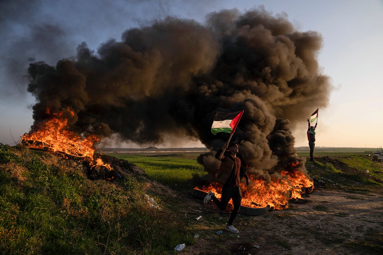 Palestijnen in de Gazastrook verbranden banden en zwaaien met de nationale vlag tijdens een protest tegen Israëlische militaire inval in de stad Jenin op de Westelijke Jordaanoever.