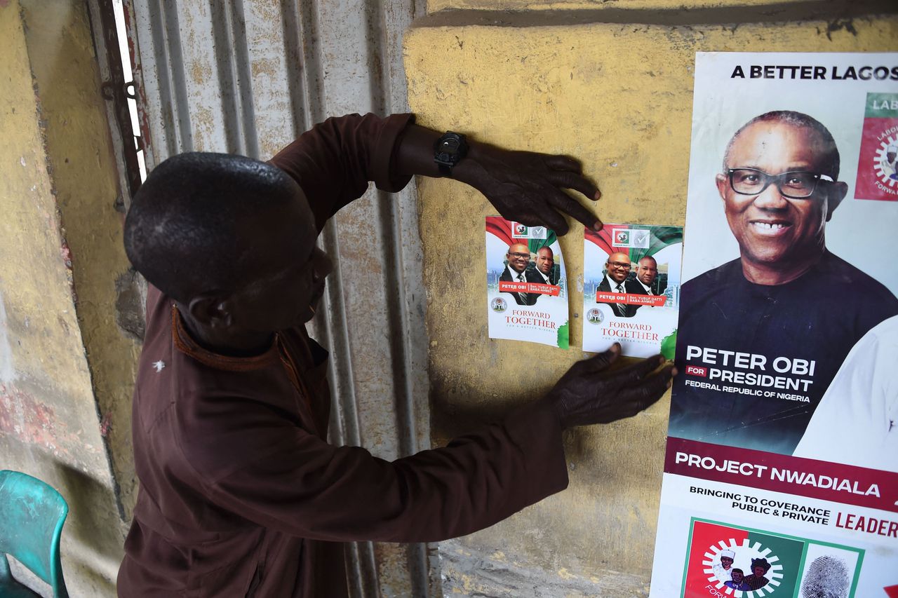 Een aanhanger van presidentskandidaat Peter Obi hangt flyers op met Obi en zijn running mate Datti Baba-Ahmed in Lagos. Op 25 februari zijn er verkiezingen in Nigeria.