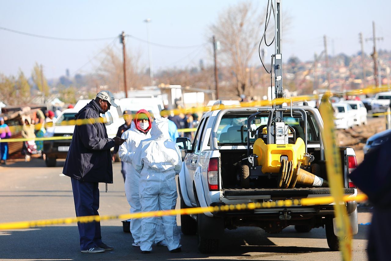 Forensische onderzoekers zijn in juli aan het werk in het Zuid-Afrikaanse Soweto na een schietpartij waarbij veertien mensen omkwamen en negen anderen gewond raakten.