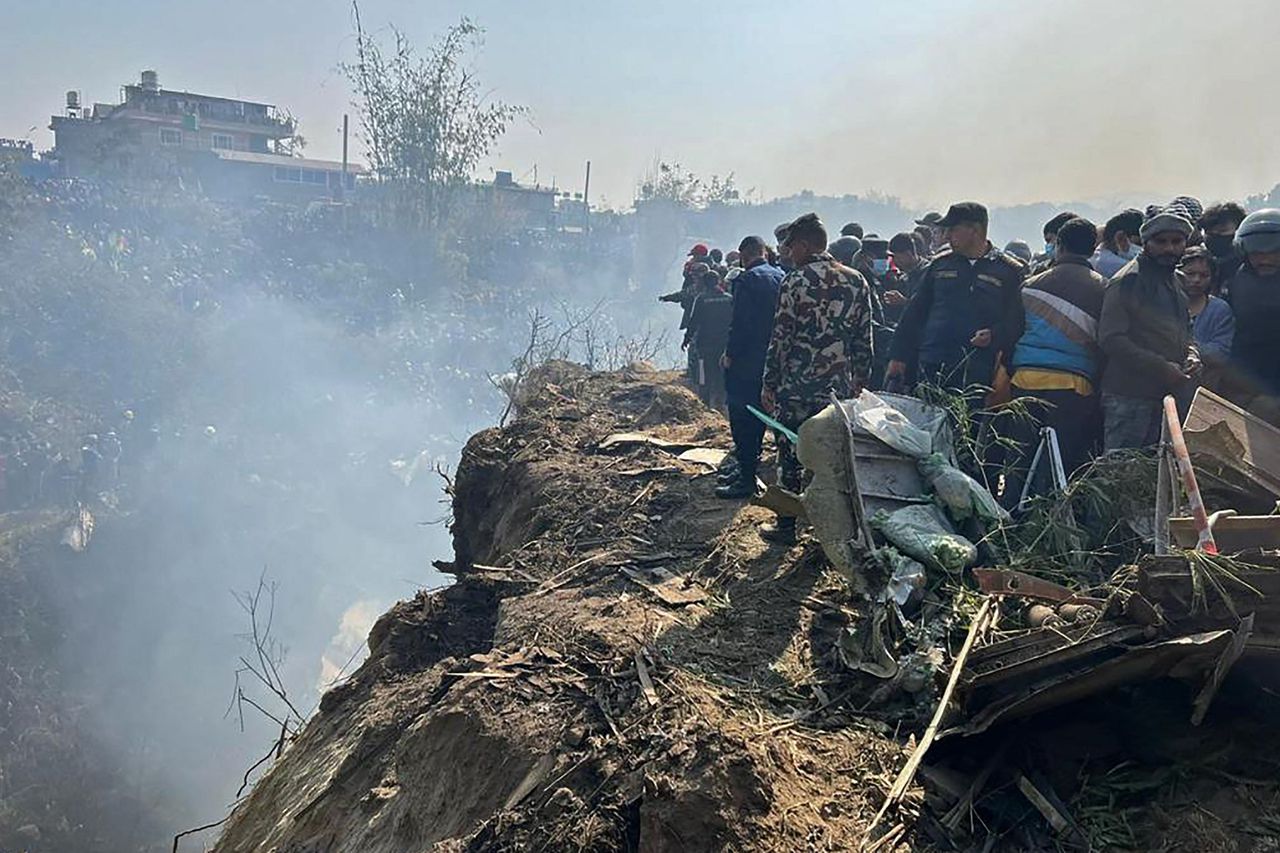 Omstanders en reddingswerkers staan bij de locatie in Pokhara waar zondag het toestel van Yeti Airlines is neergestort.