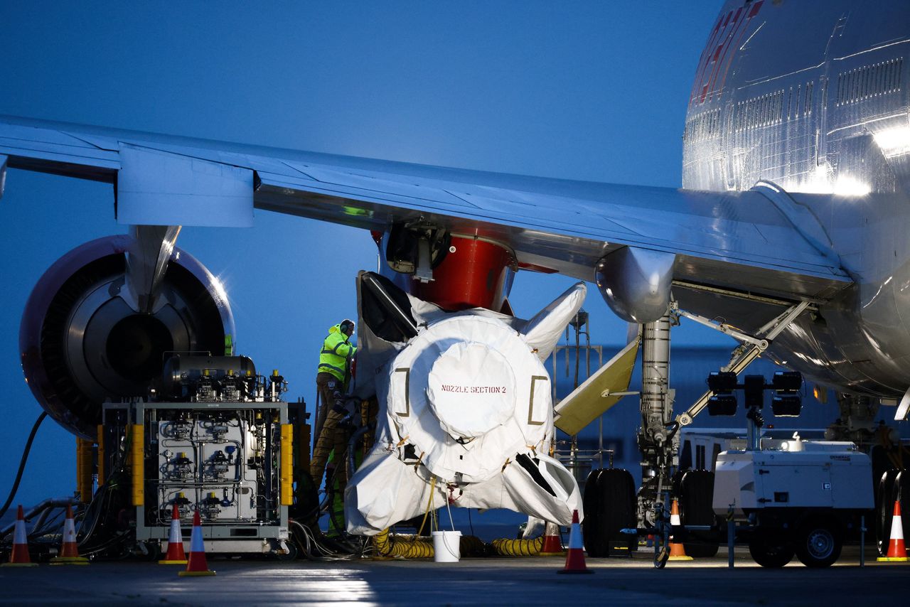 Technici werken aan de Launcher-One-raket van Virgin Orbit, bevestigd aan de vleugel van een Boeing 747-400-vliegtuig, voorafgaand aan de eerste lancering in het VK, op Spaceport Cornwall op Newquay Airport in Groot-Brittannië.