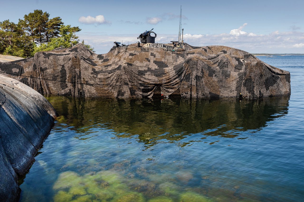 Een gecamoufleerd militair schip ligt verscholen tussen rotsen nabij Stockholm tijdens een NAVO-oefening met amfibische strijdkrachten in juni.