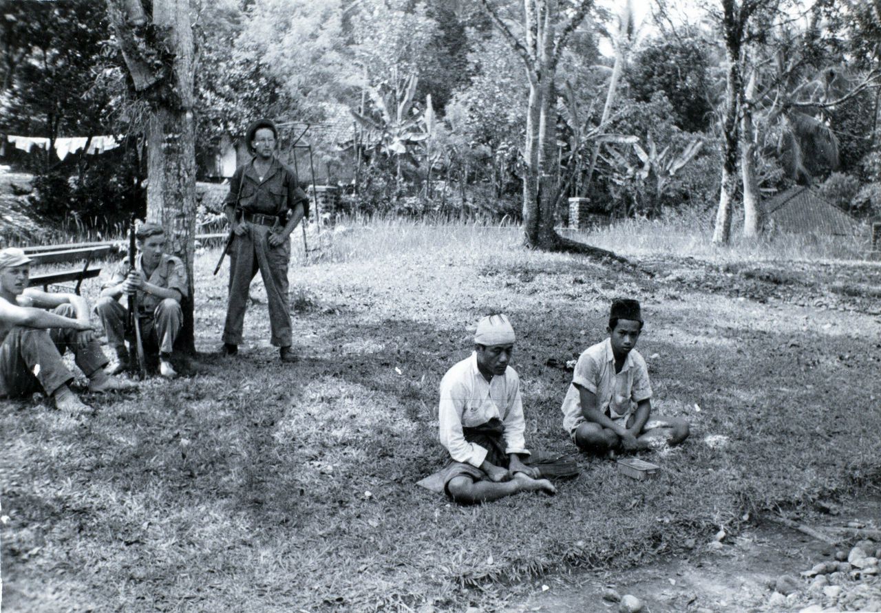 Nederlandse soldaten bewaken gevangen genomen Indonesiërs.