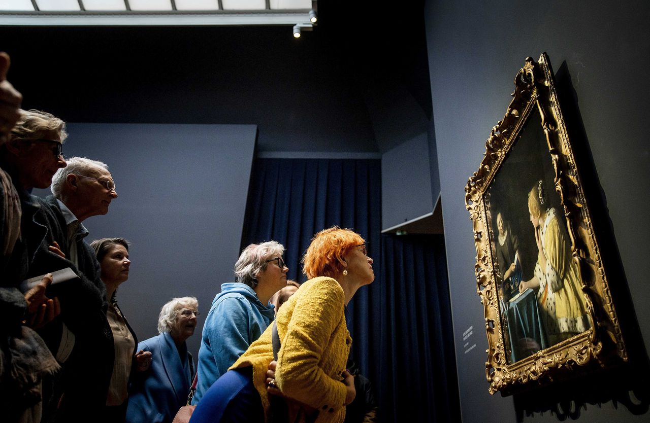 Bezoekers bewonderen Vermeers schilderij ‘Dame en dienstmeid’ tijdens de opening van de Vermeer tentoonstelling in het Rijksmuseum.