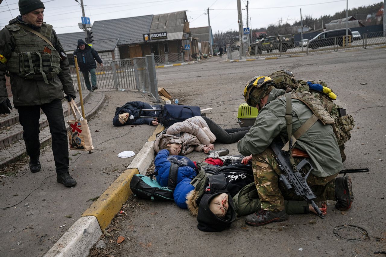 Oekraïense soldaten buigen zich over slachtoffers van een Russische mortier-aanval in Irpin, bij Kyiv, 6 maart 2022.