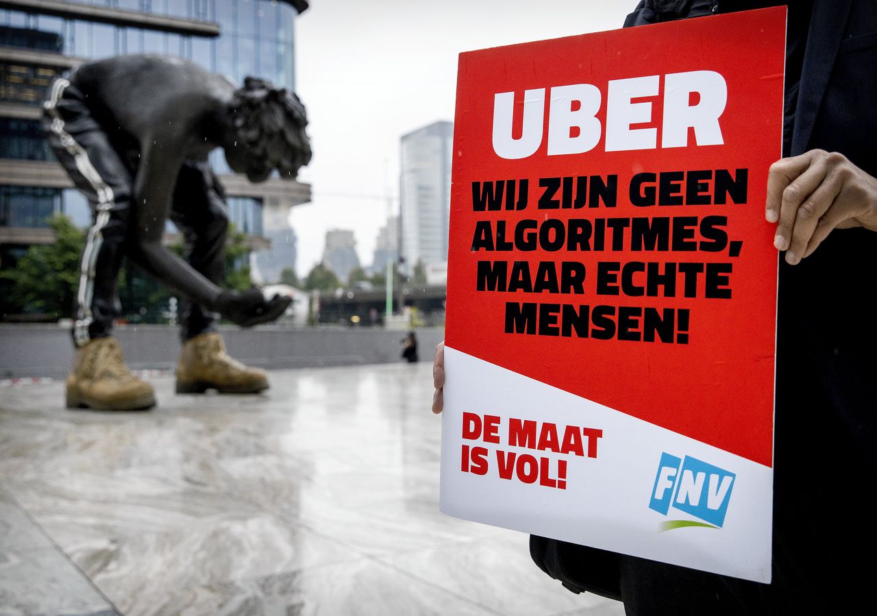 Een chauffeur van Uber houdt een protestbord omhoog bij de rechtbank voor de zitting tussen FNV en Uber over de rechten van chauffeurs.