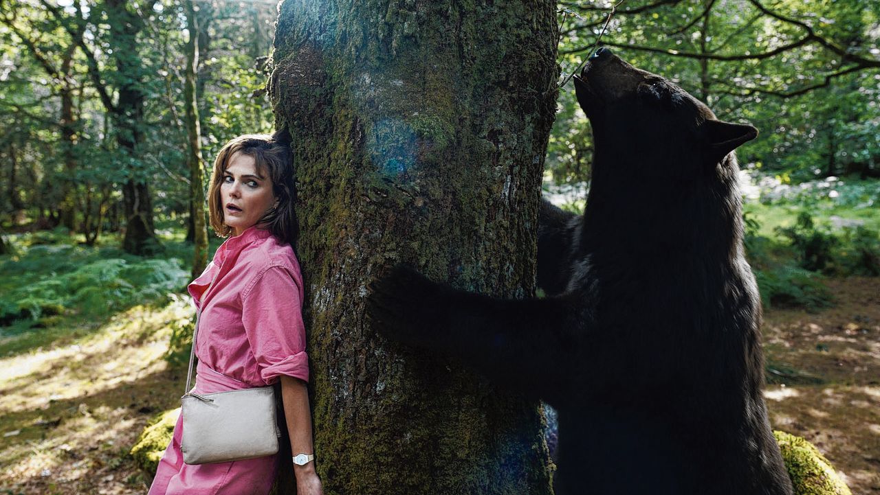 Sari (Keri Russel) schuilt achter een boom voor de cocaine bear die uit is op twee dingen: bloed en coke.