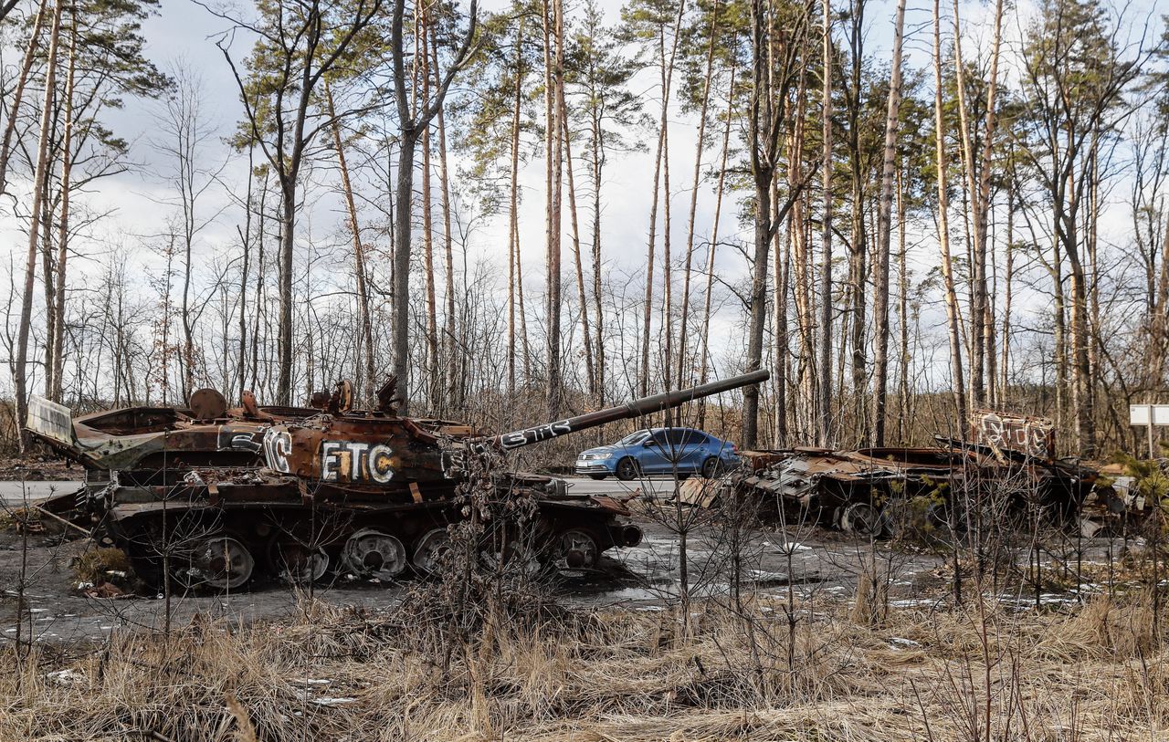 Auto’s passeren kapotte Russische militaire voertuigen die, op zo’n vijfentwintig kilometer van Kyiv, als herinnering aan de invasie blijven staan.