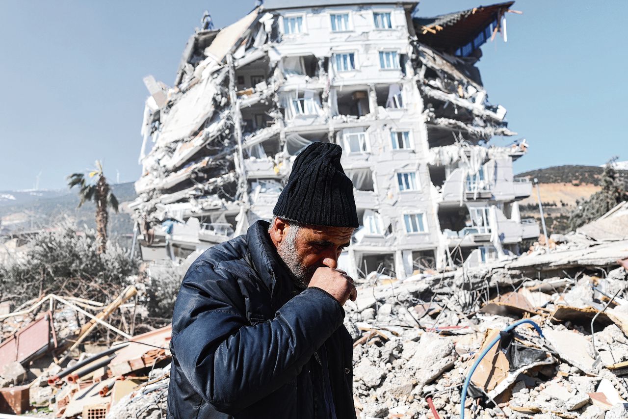 Een man loopt tussen de door de aardbeving ingestorte gebouwen van Gaziantep.