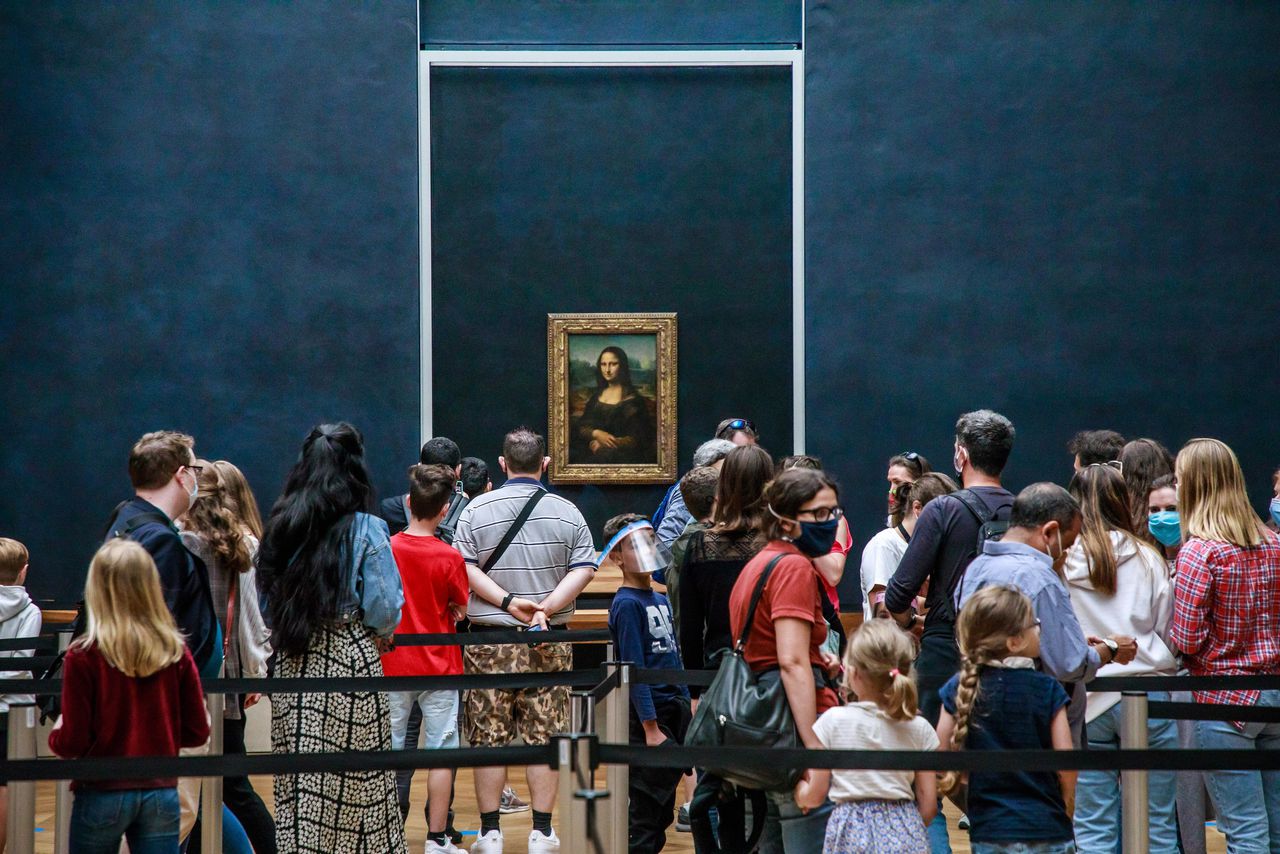 Bezoekers met mondkapjes bekijken Leonardo da Vinci's schilderij ‘La Gioconda (Mona Lisa)’ in Het Louvre, Parijs, 6 juli 2020. Die dag ging het museum na vier maanden sluiting vanwege de corona-epidemie weer open.