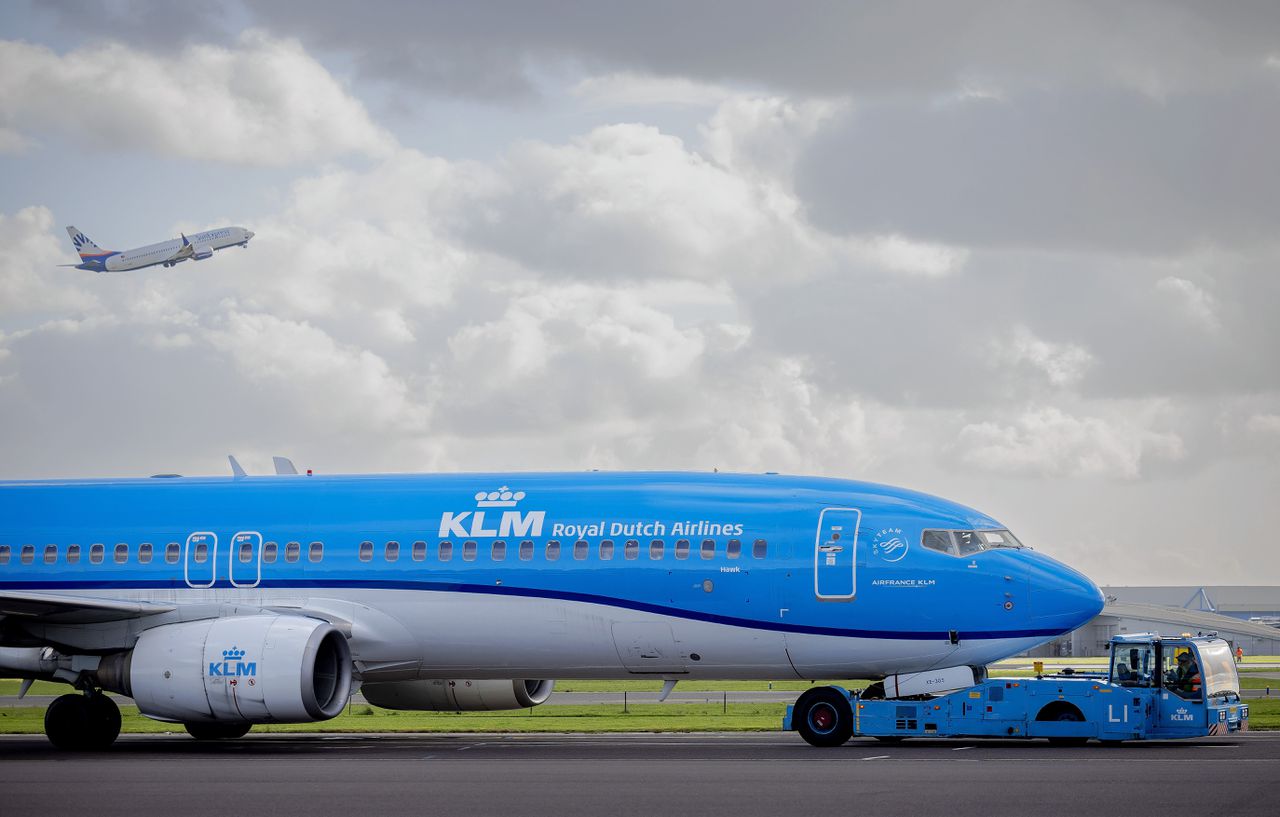 Een grondafhandelaar sleept een vliegtuig op de luchthaven Schiphol.