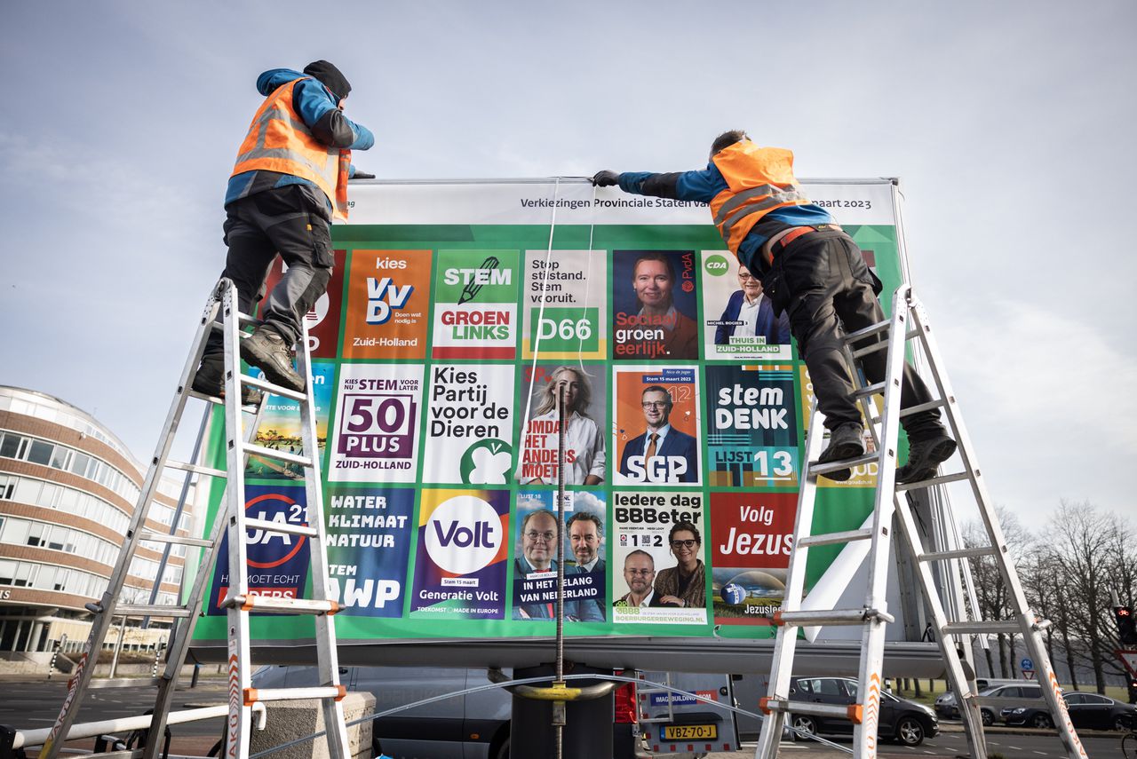 Verkiezingscampagneposter met de deelnemende partijen aan de verkiezingen wordt geplaatst in Den Haag.