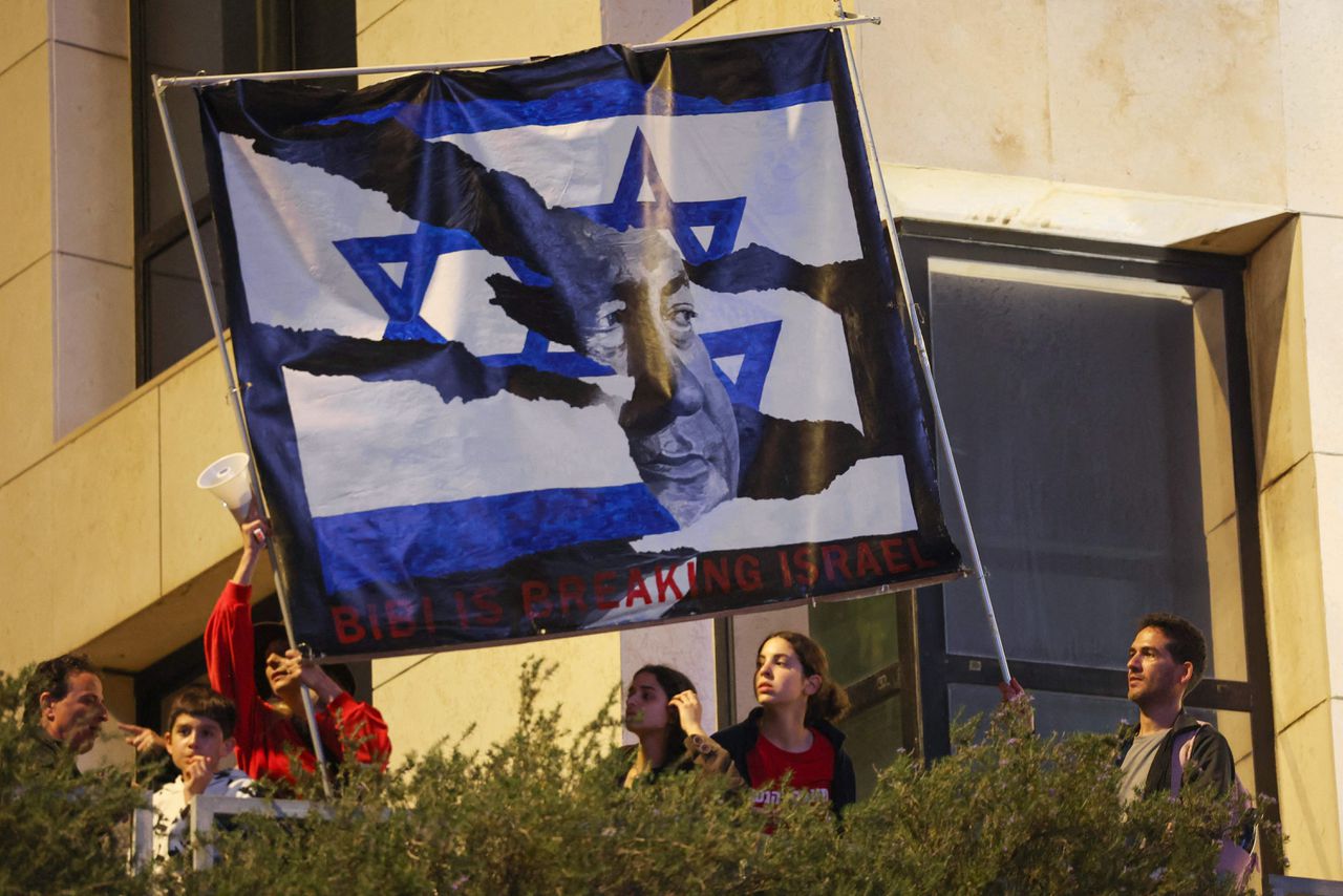 Israëlische demonstranten houden een spandoek omhoog met daarop de beeltenis van premier Benjamin Natanyahu, die de rechterlijke macht in het land wil inperken.