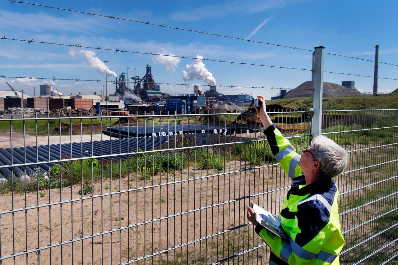 Een inspecteur van de omgevingsdienst, die toezicht houdt op Tata Steel, controleert het fabrieksterrein met een fotocamera.