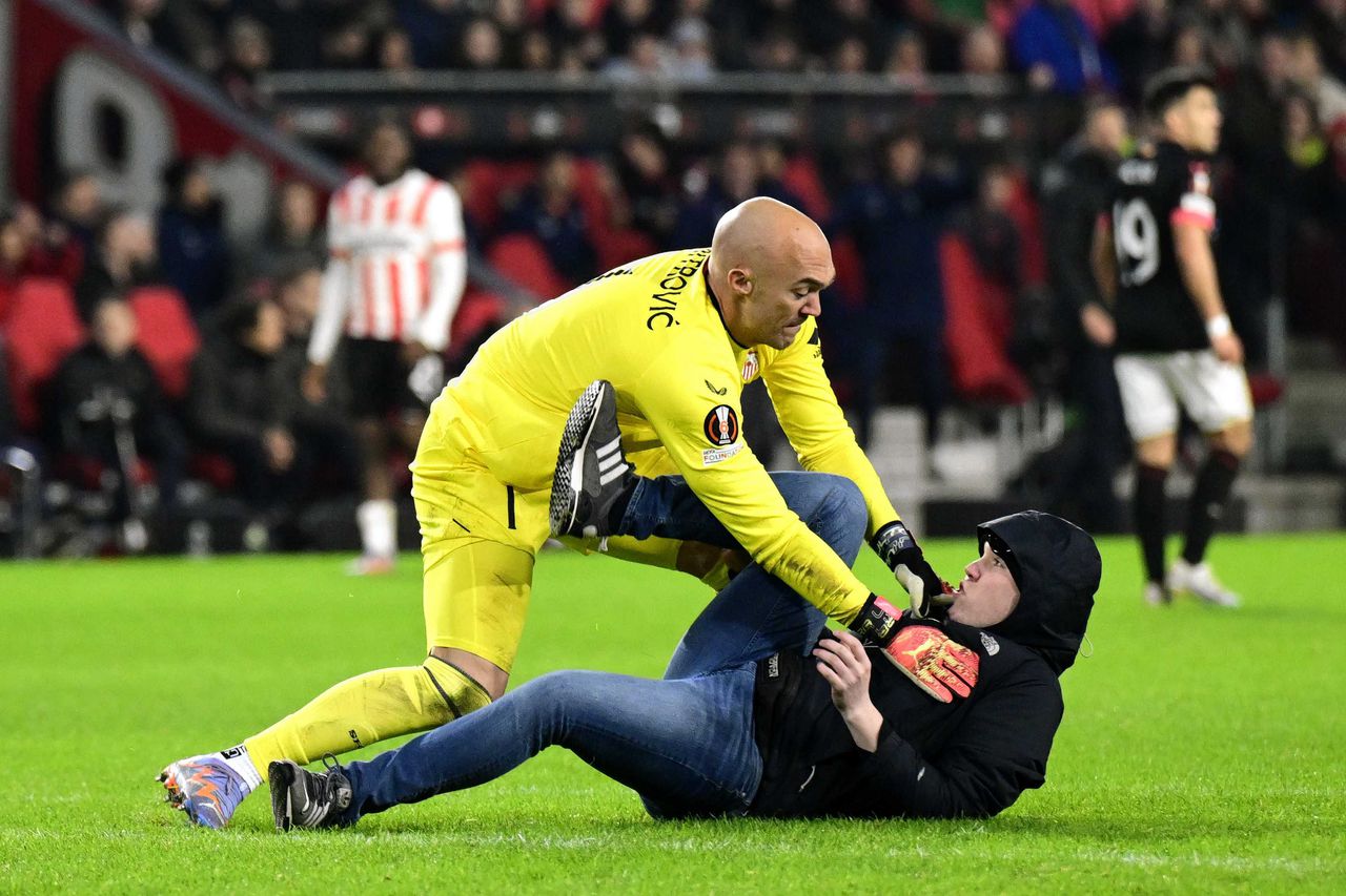 De supporter van PSV belaagt Sevilla-keeper Marko Dmitrovic.