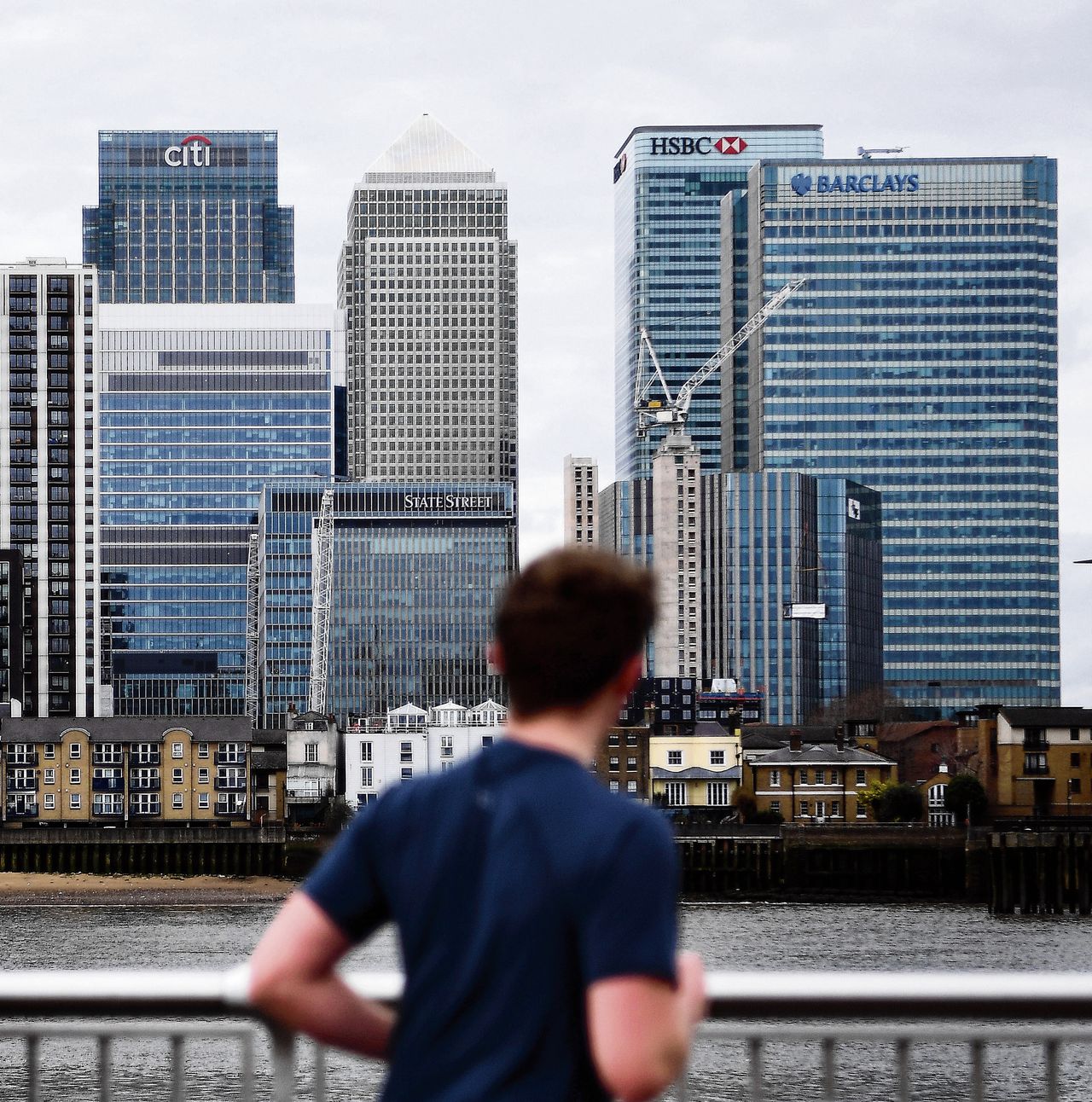 Een jogger kijkt naar de City, het financiele district van Londen, bij Canary Wharf aan de Theems.