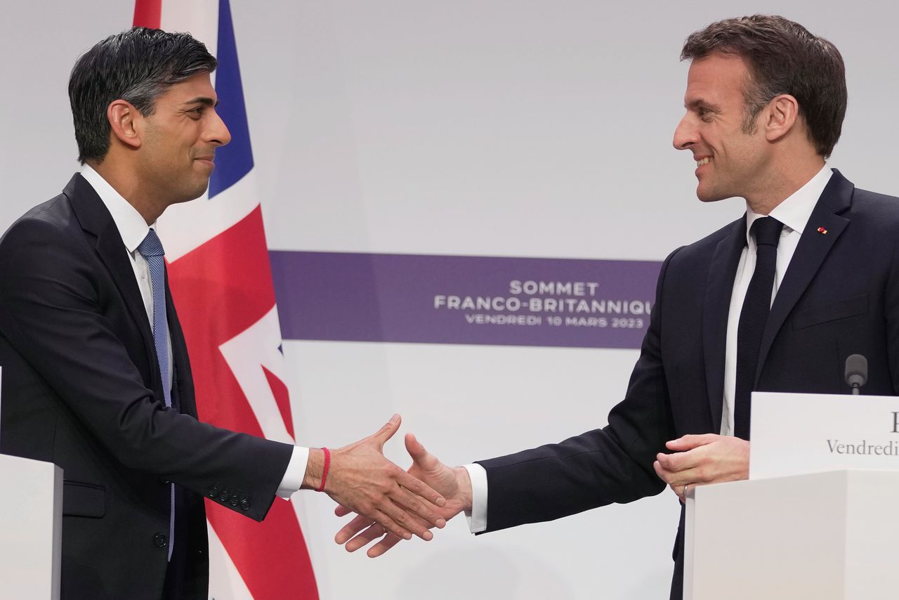 De Britse premier Rishi Sunak en de Franse president Emmanuel Macron schudden handen tijdens hun ontmoeting in Parijs vrijdag.