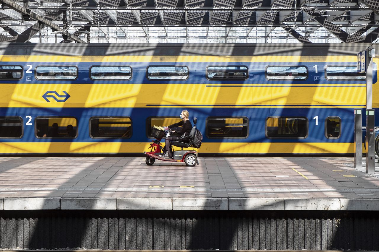 Een vrouw in een scootmobiel wacht op station Rotterdam Centraal op haar trein.