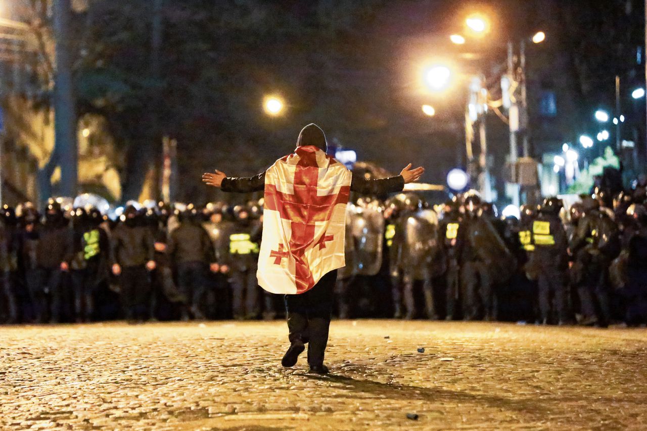 Een betoger met de Georgische vlag om daagt de oproerpolitie uit in Tbilisi, afgelopen dinsdag