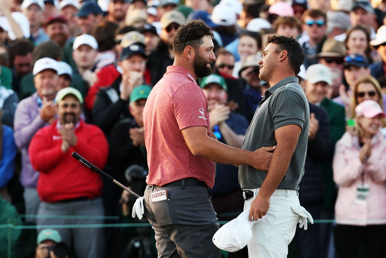 Jon Rahm (links) neemt de felicitaties in ontvangst van Brooks Koepka na zijn zege bij The Masters.