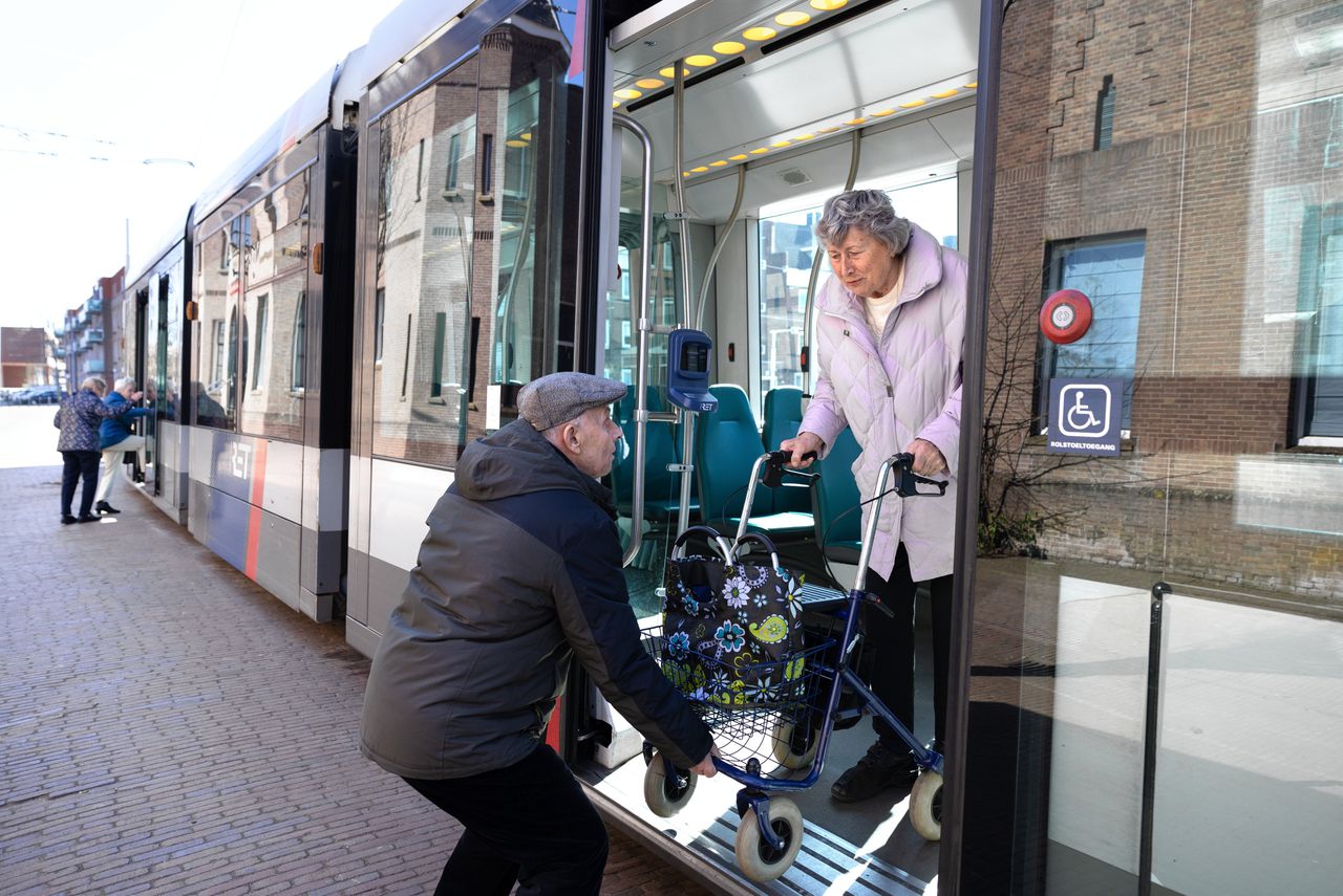 Een man helpt Carla Haslinghuis bij het uitstappen uit tram 8 in Rotterdam.