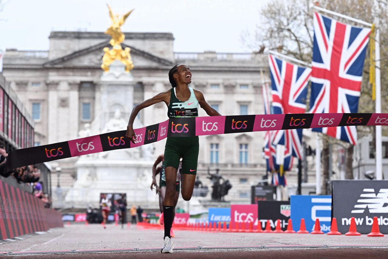 Atlete Sifan Hassan komt als eerste over de finish in Londen, met op de achtergrond Buckingham Palace.