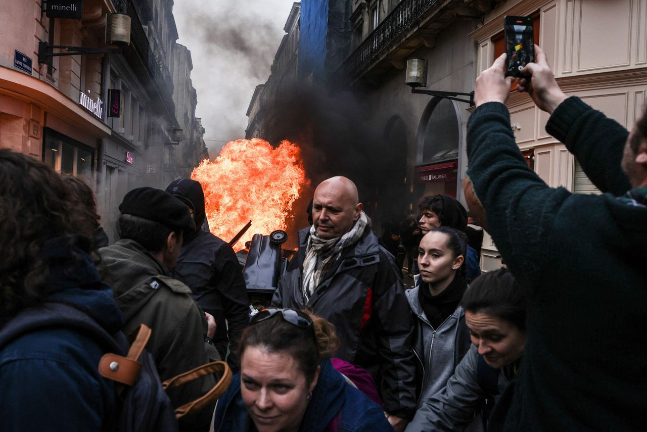 Demonstranten lopen langs brandende afvalcontainers tijdens een demonstratie in Bordeaux, 18 maart 2023.