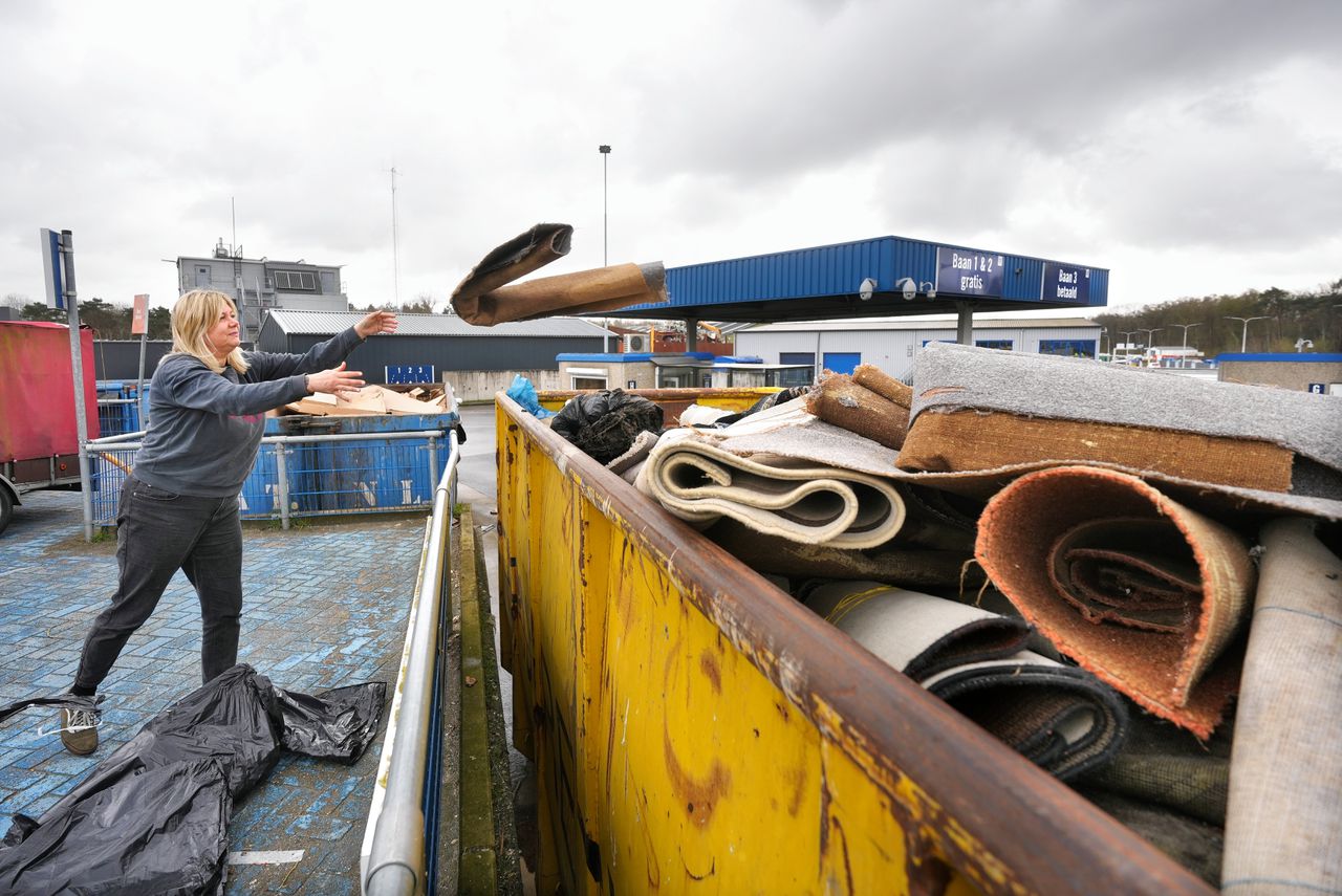 Linda Godschalk gooit een rol tapijt in de container van de milieustraat.