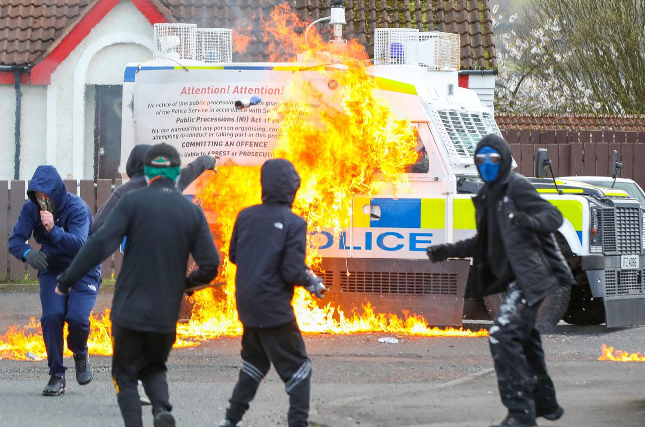 Gemaskerde jongeren zetten een politiewagen in brand met molotovcocktails in het Noord-Ierse Londonderry.