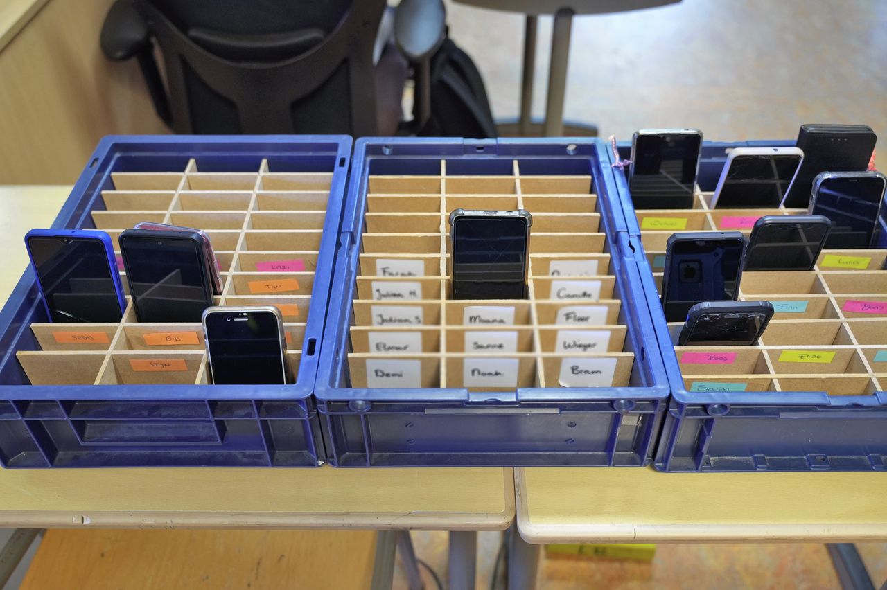 Op een school in Nijmegen moeten de mobieltjes in een bak met vakjes gedaan worden zodat er tijdens de les niet mee gespeeld of geappt kan worden.