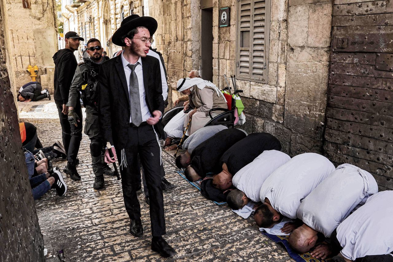 Joodse mannen lopen vrijdag met een militaire escorte door de Oude Stad van Jeruzalem waar moslims net bidden.