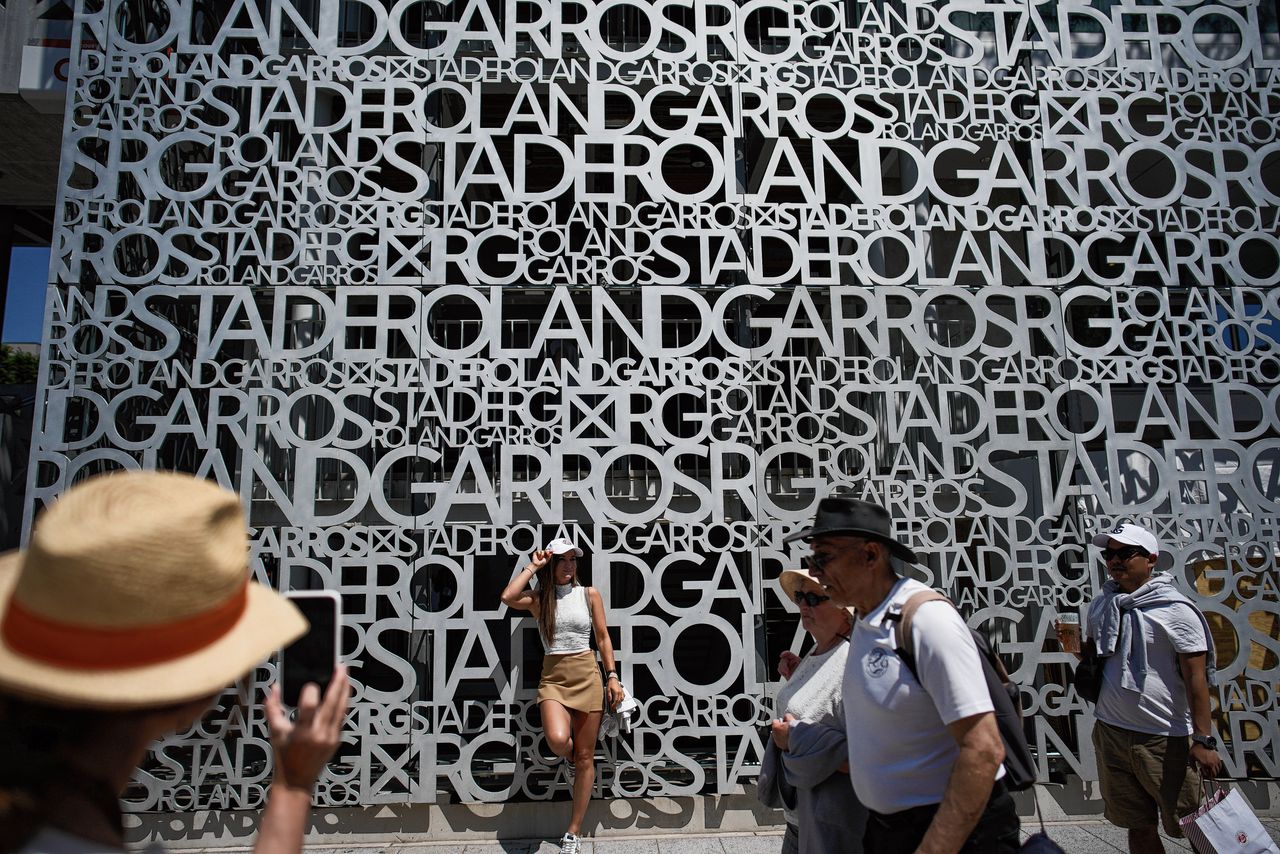 Bezoekers van Roland Garros bij een muur van het centercourt op het tenniscomplex in Parijs.