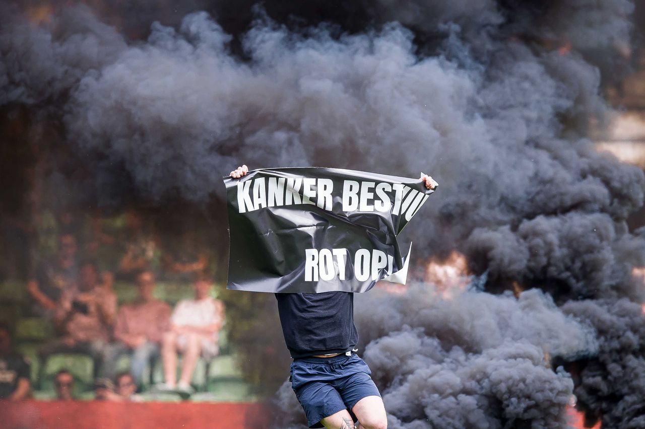 Een FC Groningen supporter tijdens de Eredivisiewedstrijd met een spandoek dat het bestuur van de club bekritiseert.