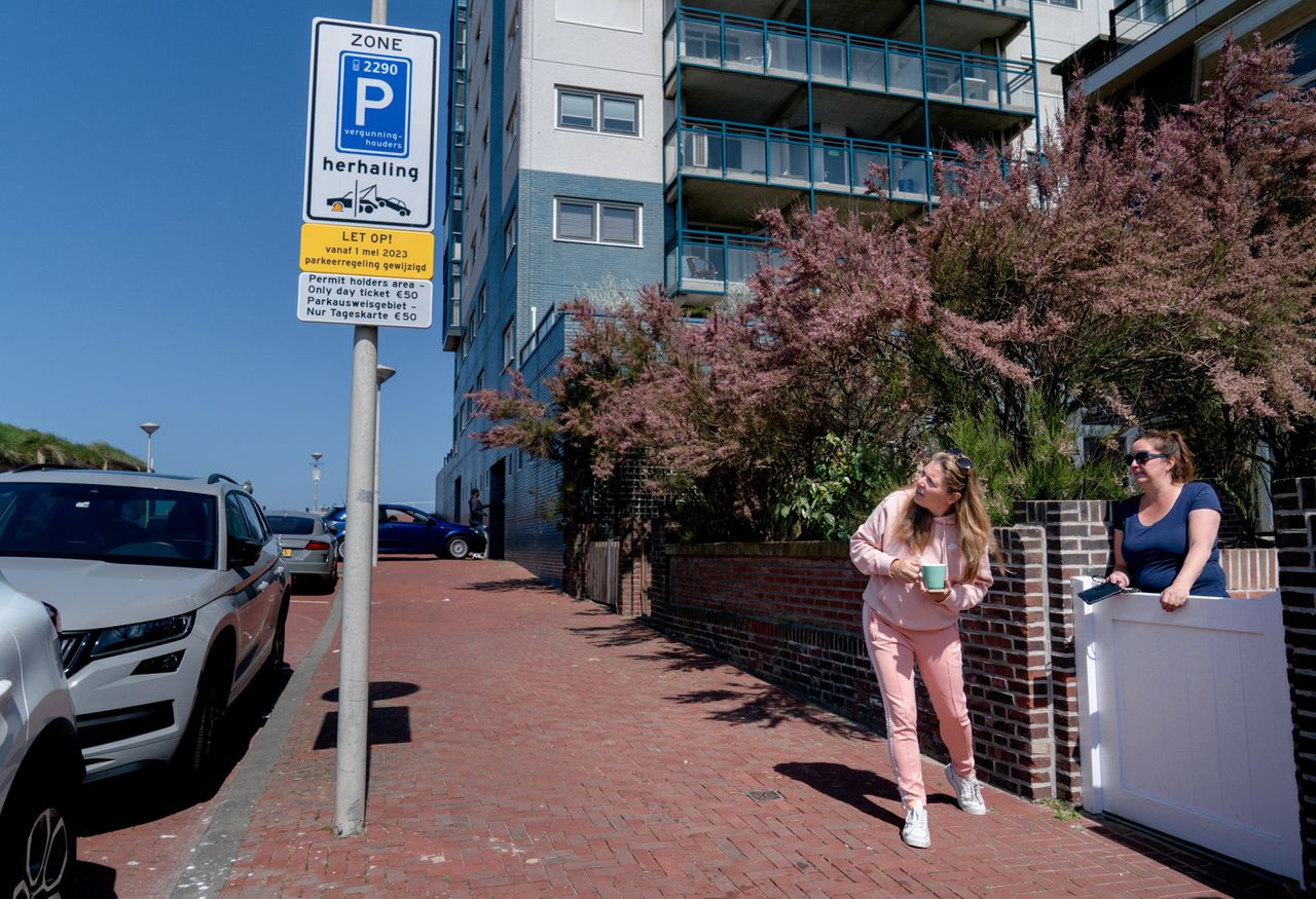 Bij een verkeersbord in Scheveningen met een waarschuwing voor nieuwe parkeerregels praten bewoners met elkaar over het parkeerbeleid.