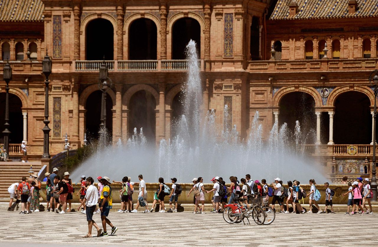 Schoolkinderen zoeken verkoeling bij een fontein in het centrum van Sevilla. Door klimaatverandering zijn de winters korter, waardoor het toeristenseizoen langer duurt.