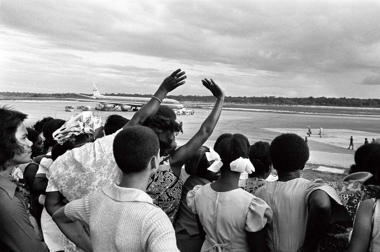 Surinamers zwaaien hun landgenoten uit die vlak voor de onafhankelijkheid van Suriname naar Nederland vertrekken.