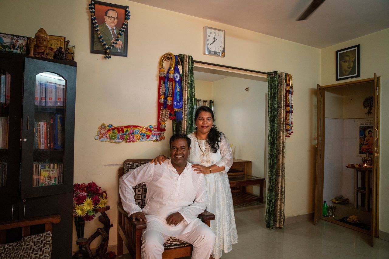 Anitha en Beerud R. Narayanswamy in hun huis in Bangalore onder het portret van de activist Bhimrao Ambedkar. Het stel bekeerde zich in 2021 tot het Boeddhisme om zo te ‘ontsnappen’ uit hun lage kaste.